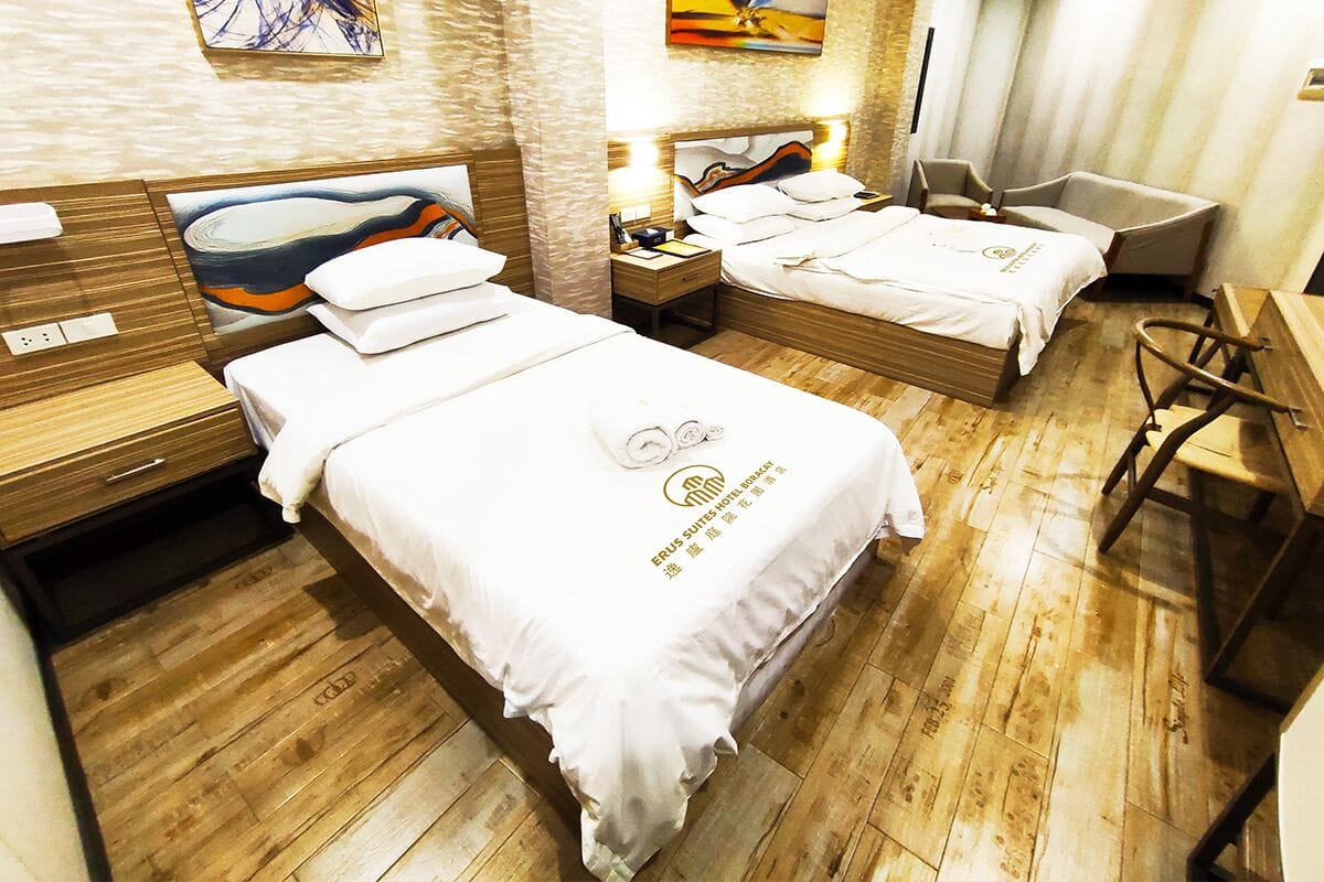 Une chambre d’hôtel avec deux lits, un plancher en bois et des œuvres d’art accrochées aux murs.