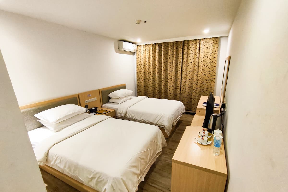 Une chambre d’hôtel avec deux lits, un bureau avec un ordinateur, une machine à café et un miroir.