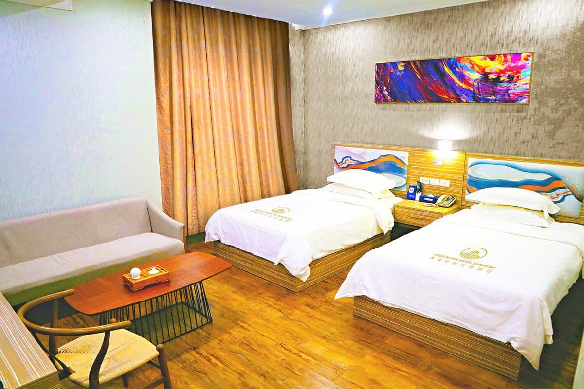 Une chambre d’hôtel avec deux lits, un canapé, une petite table et une chaise.