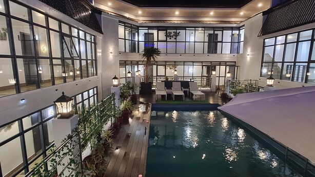 A multi-level indoor pool area with a central water feature, surrounded by seating and potted plants. -  ERUS SUITES HOTEL BORACAY (Boracay Island)