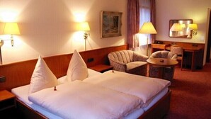 A hotel room with a large bed, two armchairs, a small table, and two lamps. - Hotel Buck (Bad Urach)