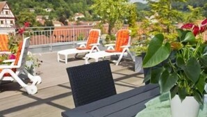 A wooden deck with outdoor seating, a table, and a potted plant. - Hotel Buck (Bad Urach)