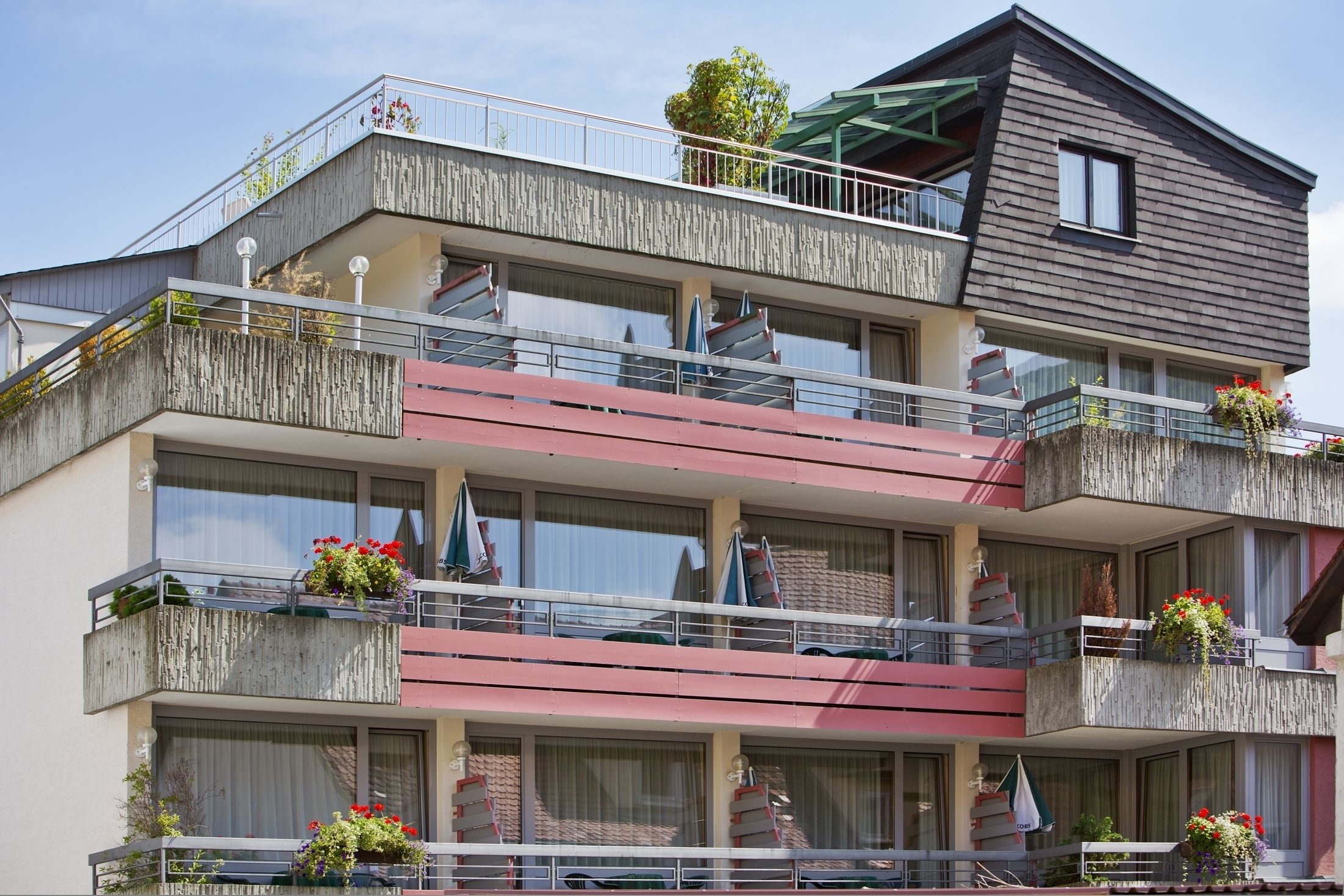 Een meerlaags gebouw met balkons, waarvan sommige planten en parasols hebben.