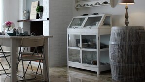A dining area with a white table, chairs, a glass display case, and a decorative barrel. - B&Be Home (Tollo)