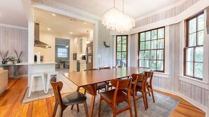 A dining area with a large wooden table, six chairs, and a chandelier.