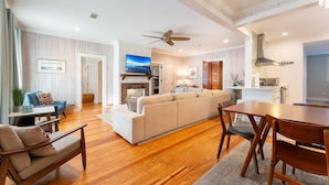 A spacious living room with a sofa, a TV, and a dining area with a table and chairs.