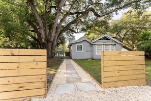 A pathway leading to a house with a porch, surrounded by trees. - Pet-Friendly Beach Cottage on St. Simons Island | Walk to Beach & Pier Village (St Simons)