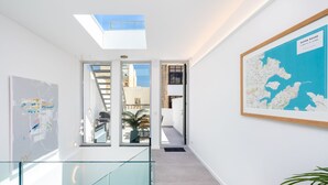 A modern interior with a glass staircase, a map on the wall, and a skylight.