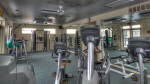 A gym with stationary bikes, weight machines, and a ceiling fan.