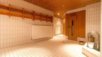 A spacious room with a wooden ceiling, tiled walls, and a large window.