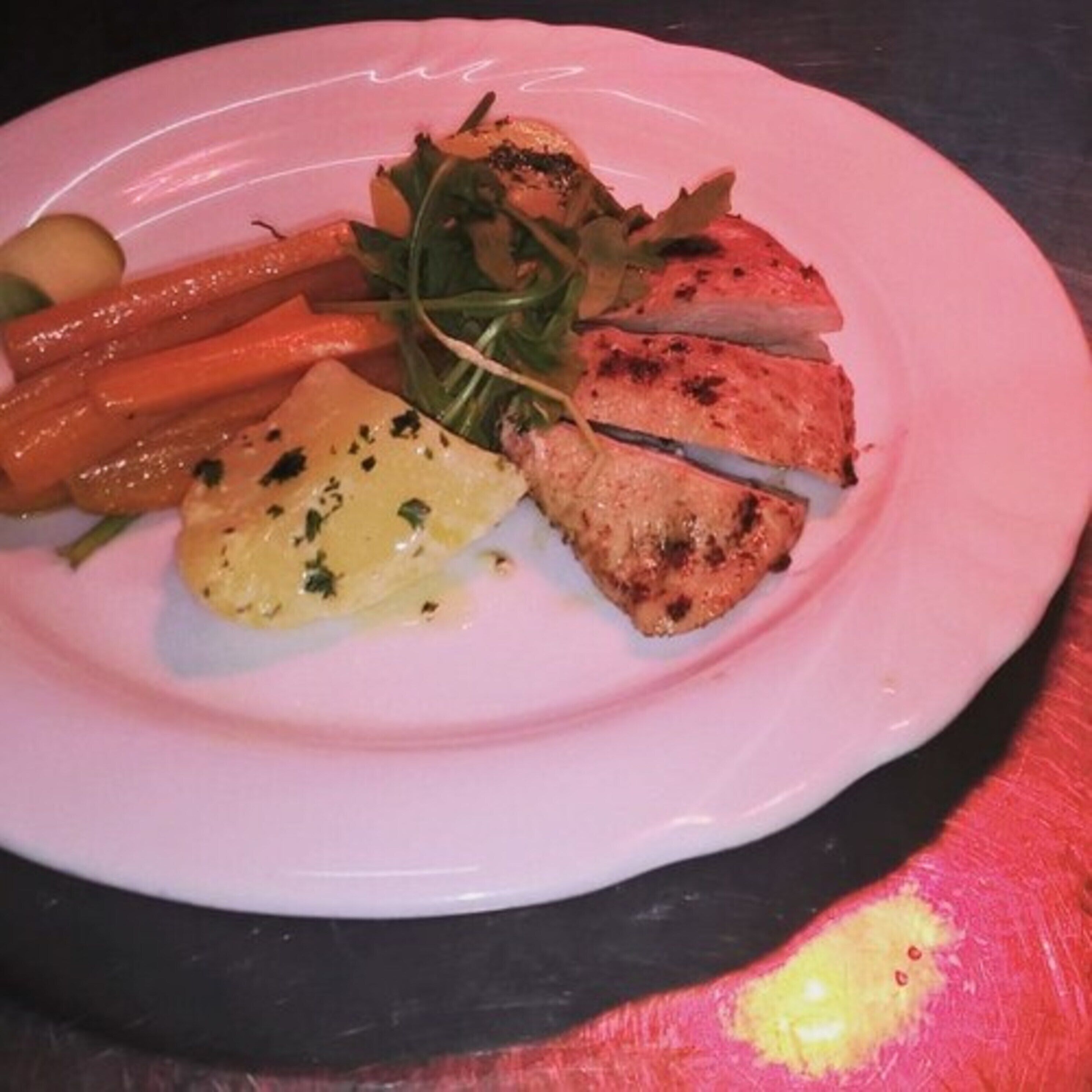 Ein Teller mit gegrilltem Hähnchen, Karotten und Grünzeug.