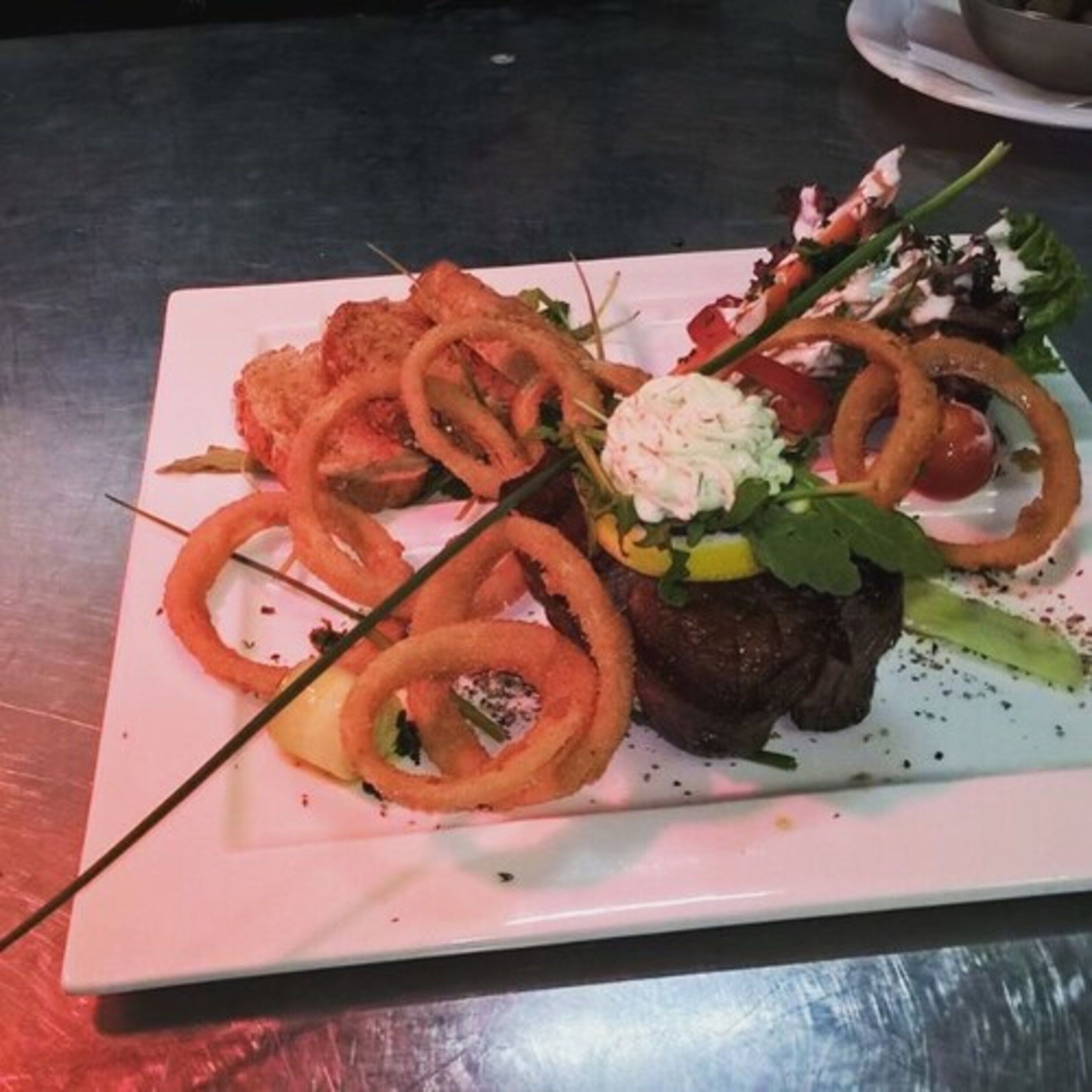 A plate of food with various items including onion rings, a meat dish, and a salad.