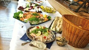 A buffet table with various dishes including a large platter of prosciutto and melon, salads, and other appetizers. - Hotel Sauerbrey (Osterode am Harz)