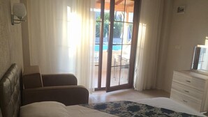 Un dormitori amb un llit, un sofà, una petarrera i vista a una piscina.