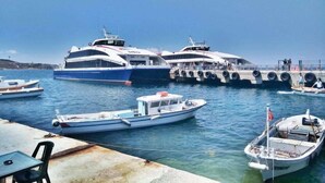 Una marina amb diversos vaixells amarrats, entre ells un iat gran blanc i blau, un vaixell blanc més petit i un llanç motor.