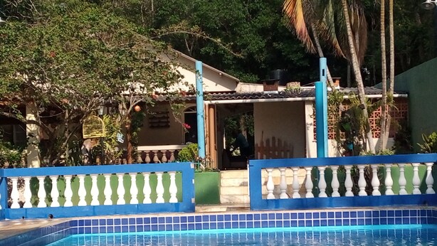 Ein Swimmingpool mit blauer Fliesenbordur, einer weißen Brüstung und einem Gebäude mit Balkon im Hintergrund.