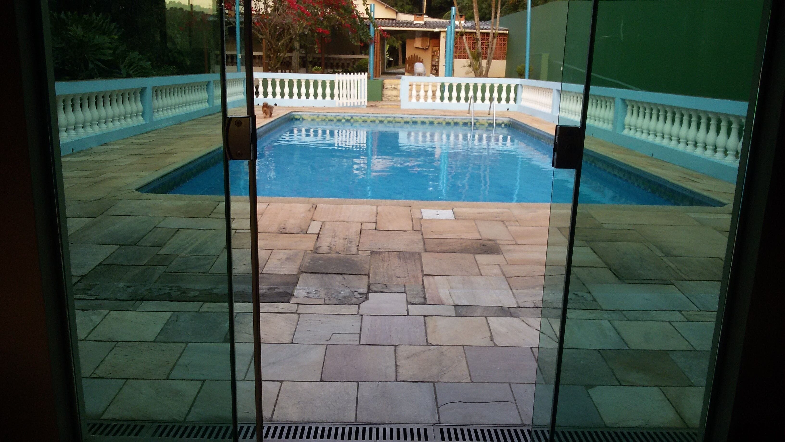 A swimming pool with a stone deck and a white fence.