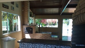 Eine Küche mit gefliestem Rücksprung, einem Backofen aus Ziegeln und einem Fenster mit Blick auf einen Garten.
