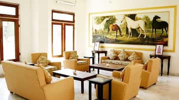 A spacious living room with a large painting of horses, multiple sofas, and a coffee table.