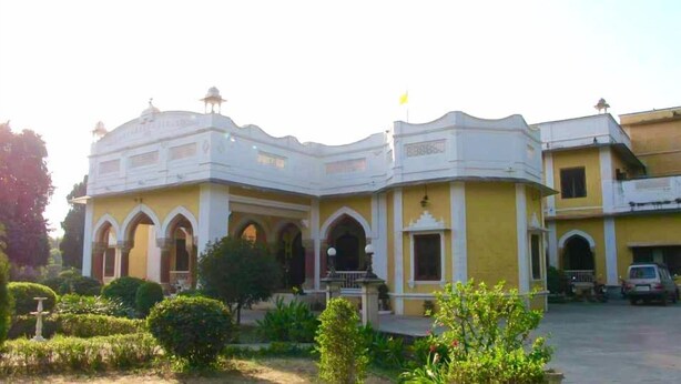 A building with a yellow facade, multiple arches, and a small garden area with a fountain. - Bhanwar Vilas Palace (Karauli)