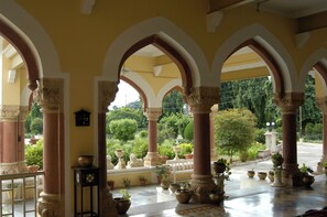 A covered outdoor area with arches, columns, and potted plants. - Bhanwar Vilas Palace (Karauli)