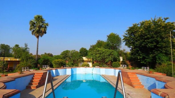 A rectangular swimming pool with a clear blue water surface, surrounded by a low brick wall and metal handrails. - Bhanwar Vilas Palace (Karauli)