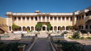A courtyard with a central pathway leading to a building with multiple arches and columns. - Bhanwar Vilas Palace (Karauli)