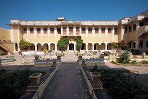 A courtyard with a central pathway leading to a building with multiple arches and columns. - Bhanwar Vilas Palace (Karauli)