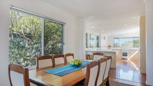 A dining area with a wooden table, chairs, and a bowl of fruit. - Heart of Peregian, 19 Piper Street, Peregian Beach, Noosa Area (Peregian Beach)