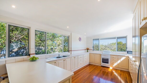 A modern kitchen with large windows, wooden flooring, and white cabinetry. - Heart of Peregian, 19 Piper Street, Peregian Beach, Noosa Area (Peregian Beach)