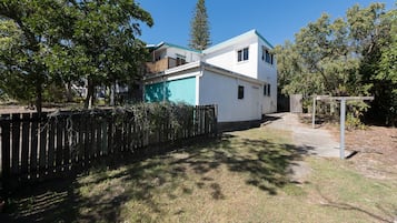 A two-story residential building with a covered patio and a fenced yard.