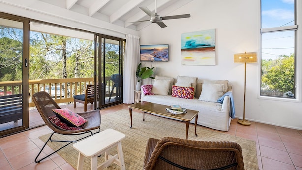 A spacious living area with a balcony, a sofa set, a coffee table, and a television. - Galleries - 1/28 Peregian Esplanade - Peregian Beach (Peregian Beach)