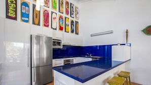 A modern kitchen with a central island, stainless steel appliances, and a blue backsplash. - Galleries - 1/28 Peregian Esplanade - Peregian Beach (Peregian Beach)