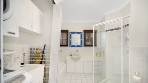 A modern bathroom with a glass shower, a white sink, and a colorful children's bath mat. - Notre Reve - 2/4 Brolga Place (Peregian Beach)