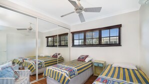 A room with three beds, a ceiling fan, and a large mirror. - Notre Reve - 2/4 Brolga Place (Peregian Beach)