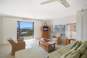 A living room with a television, a ceiling fan, and a view of the ocean. - Kari 3 - 3/7 Peregian Esplanade (Peregian Beach)
