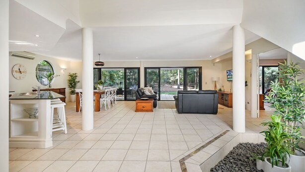 A spacious living area with a dining table, sofas, and a kitchen area with a sink and stove. - Home Away From Home, 38 Redwood Avenue, Marcus Beach, Noosa Area (Marcus Beach)
