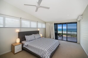 A bedroom with a bed, nightstands, a ceiling fan, a large window with curtains, and a view of the ocean. - 41 Pelican Street, Peregian Beach, Noosa Shire (Peregian Beach)