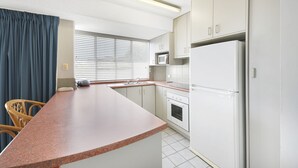 A compact kitchen with a built-in oven, a microwave, and a refrigerator.