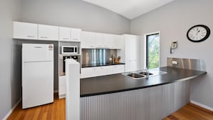 A modern kitchen with white cabinetry, a stainless steel island, and a built-in oven. - 40 Jacana Street, Peregian Beach (Peregian Beach)