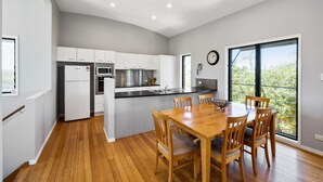 A modern kitchen with white cabinetry, a stainless steel refrigerator, a microwave, and a large island with seating. - 40 Jacana Street, Peregian Beach (Peregian Beach)