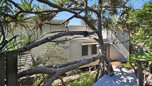 A house surrounded by dense foliage, with a visible garage and a wooden deck.