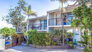 A two-story building with a balcony on the upper floor, surrounded by lush greenery and a fenced pool area. - Lyrona - 3/35 Avocet Parade (Peregian Beach)