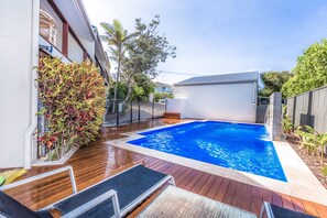 A rectangular swimming pool with a wooden deck and a blue mat in the center.