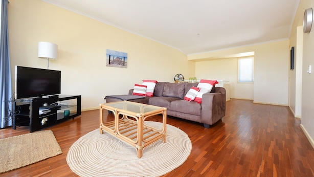 A living room with a sofa, TV, and a small table with a woven rug.