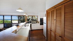 Una cocina moderna con una isla grande, armarios de madera y vista al océano.
