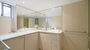 A modern bathroom with two sinks, a large mirror, and a shower area.