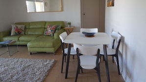 A living room with a green sofa, white chairs, a small table with a bowl, a fluffy rug, and a mirror on the wall. - Unit 2 at 4 Pelican Street, Peregian Beach, Noosa Area (Peregian Beach)