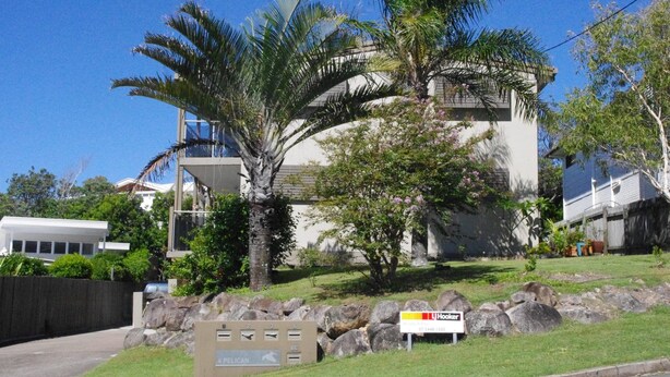 A modern two-story building with a balcony, surrounded by lush greenery and palm trees. - Unit 2 at 4 Pelican Street, Peregian Beach, Noosa Area (Peregian Beach)