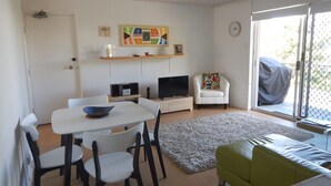 A living room with a dining table, chairs, a sofa, a TV, and a fireplace. - Unit 2 at 4 Pelican Street, Peregian Beach, Noosa Area (Peregian Beach)